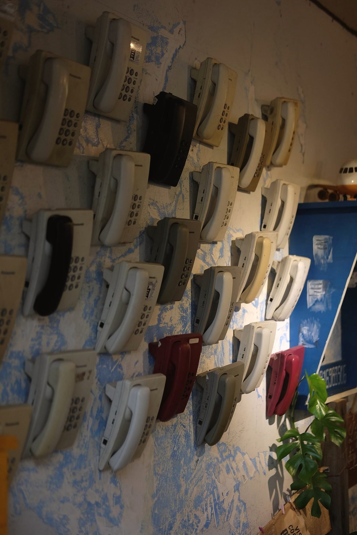 A display of retro telephone handsets on a wall.